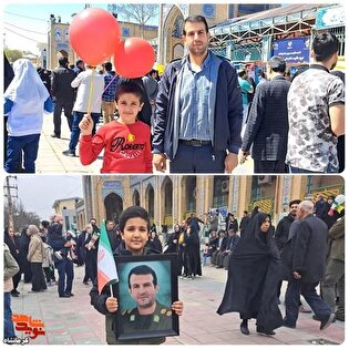 فرزند شهید «رامین مهدی آبادی» در راهپیمایی ۲۲ بهمن با قاب عکس پدر شهیدش حاضر شد